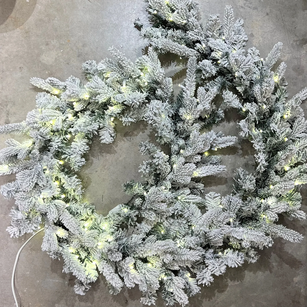 Flocked Christmas garland with lights on a concrete surface