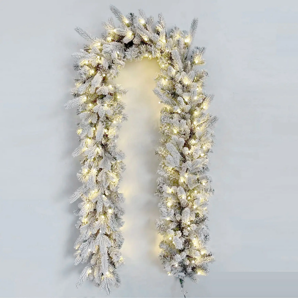 Flocked Christmas garland with lights on a plain background